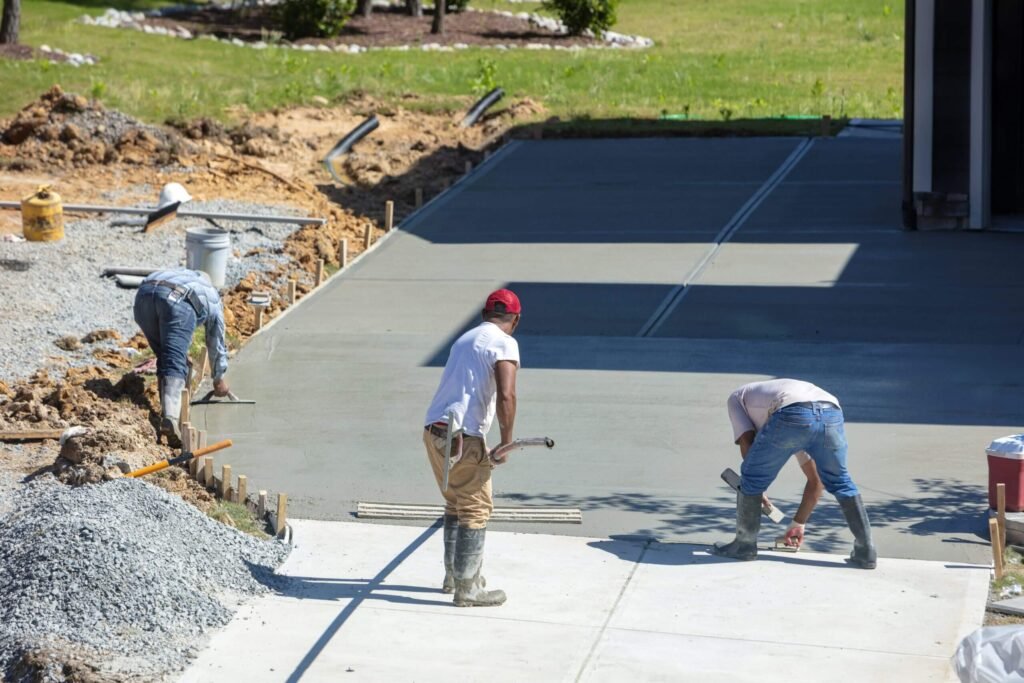 Workers leveling freshly poured concrete on a driveway at a residential property in Rochester, MN